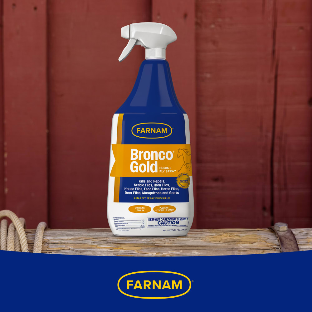 Bottle of farnam bronco gold equine fly spray sitting on a wooden log